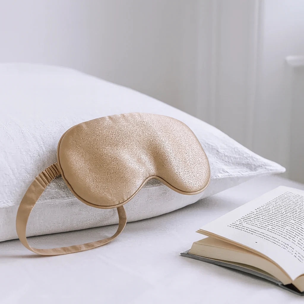 Masque de nuit en soie champagne posé sur l'oreiller