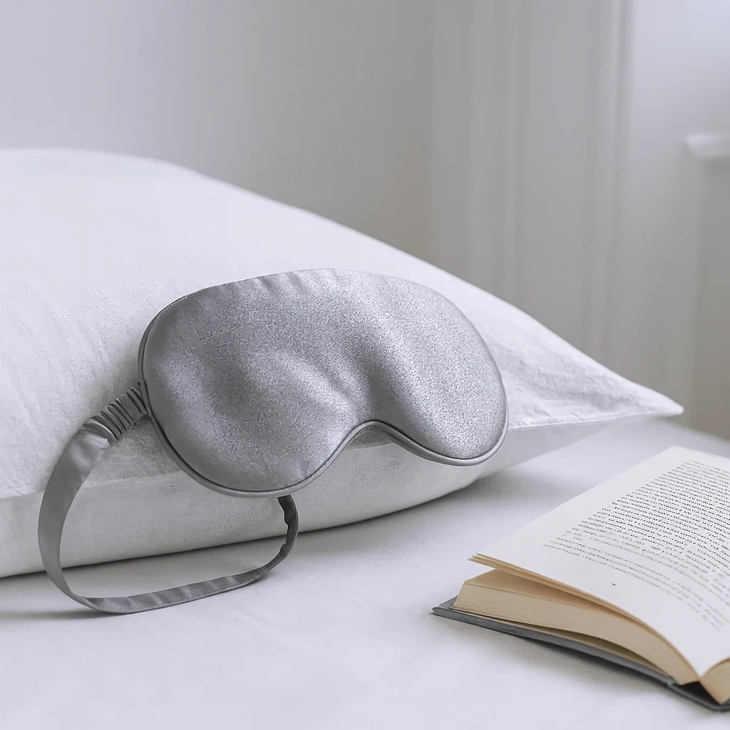 Masque de nuit en soie gris argent posé sur l'oreiller